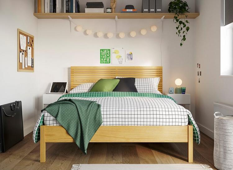 A wooden small double bed, styled in a teen room with warm wooden accents, fairy lights and green decor against white walls.