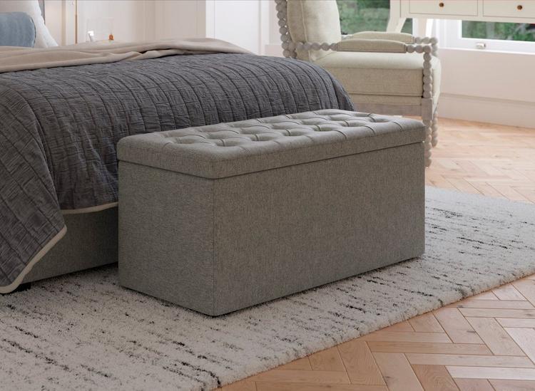 Grey soft touch blanket box with buttoned details sat at the foot of a bed