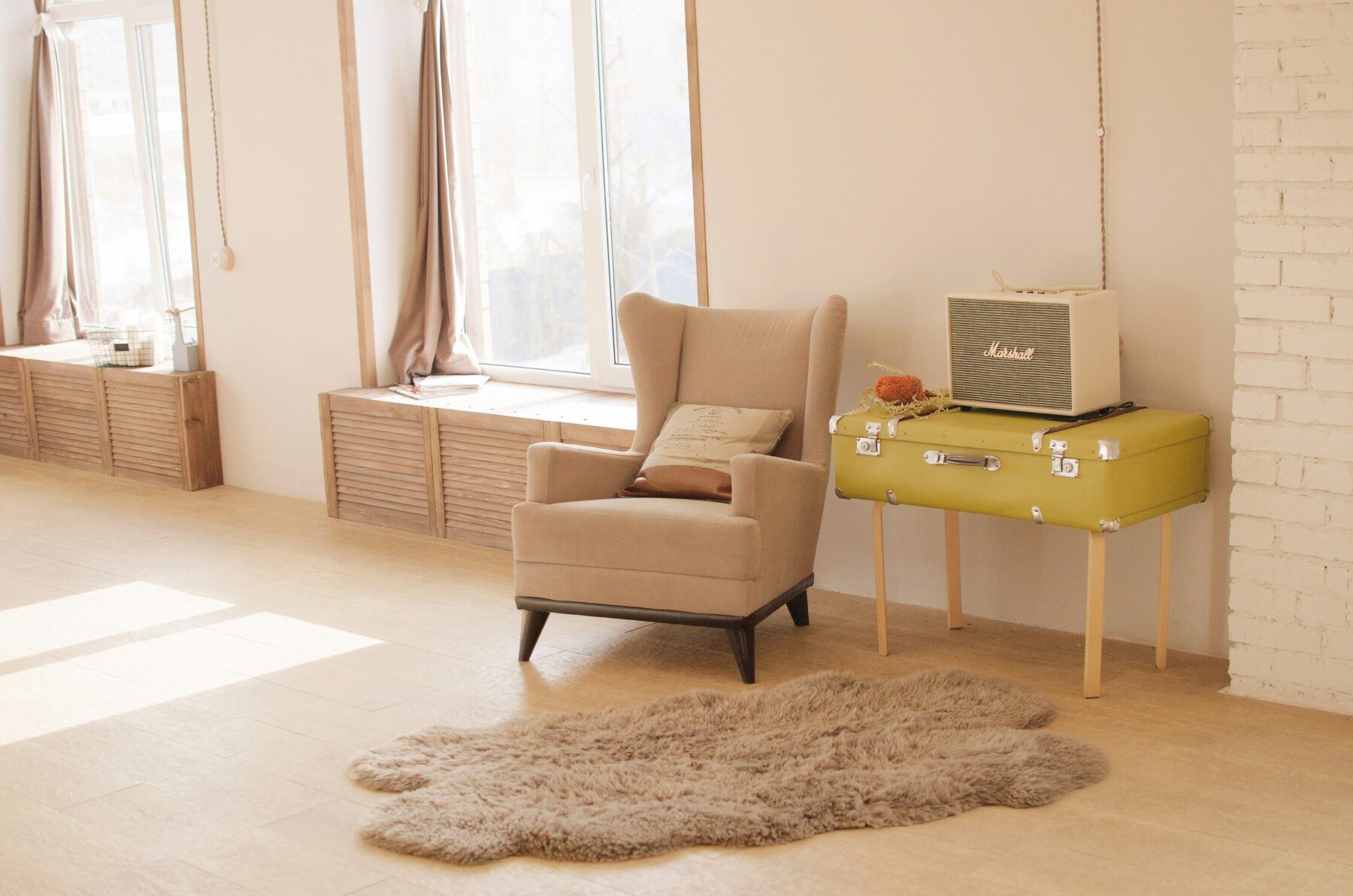 Light and airy bedroom corner featuring an armchair, rug and a radio