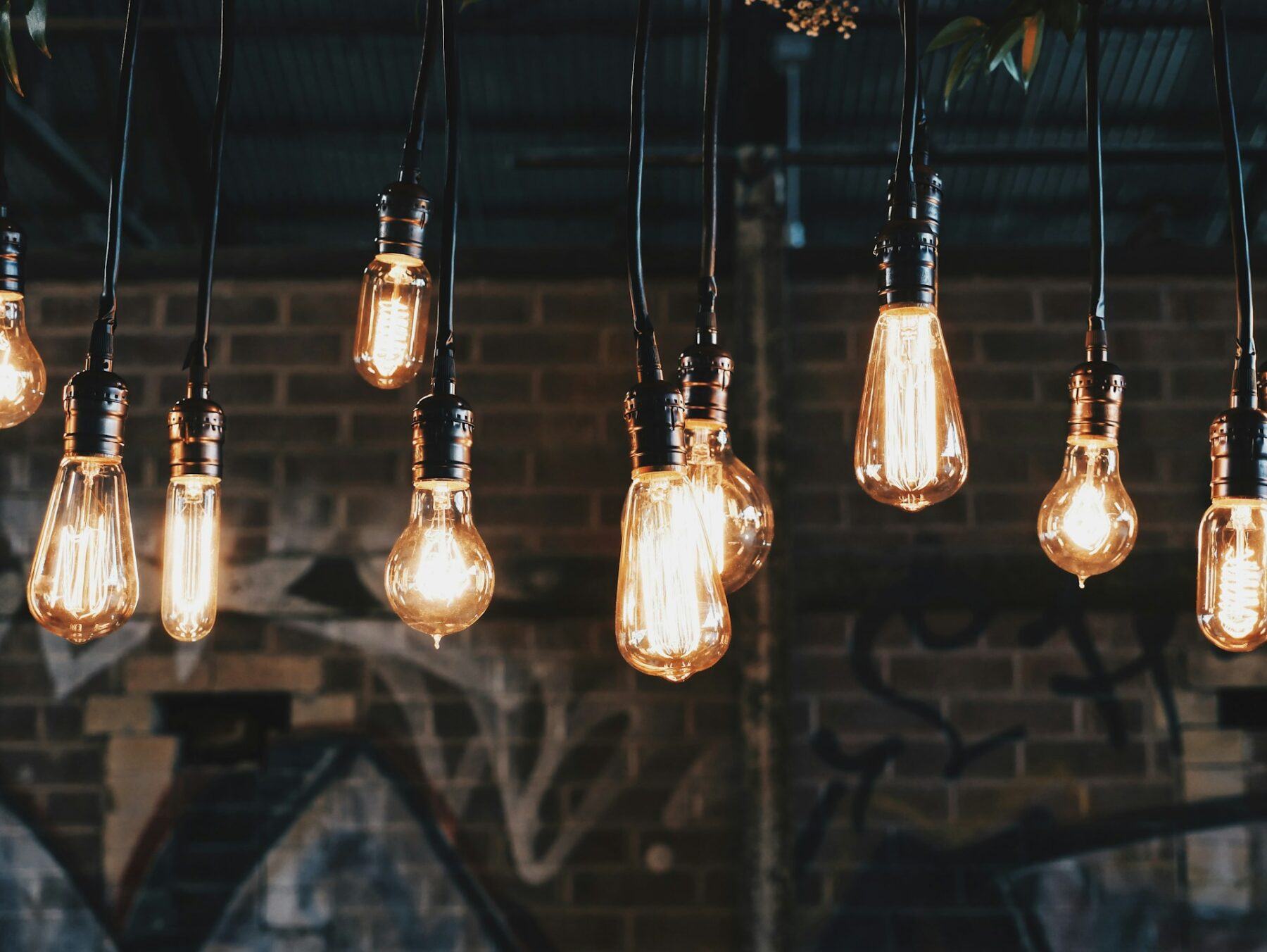 an image hanging lights with exposed bulbs against a brick wall backdrop