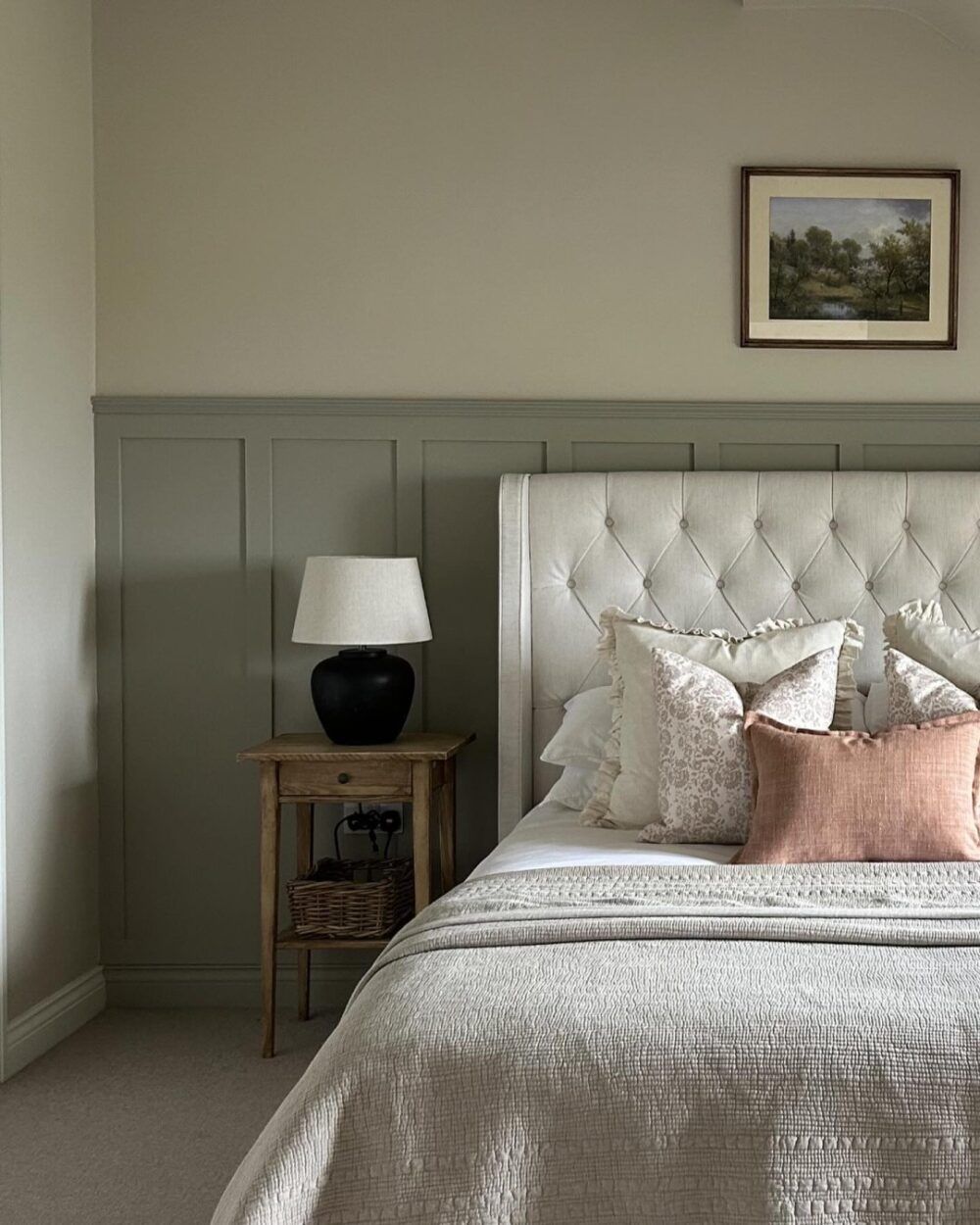 image of a zoomed in bed frame with a chesterfield style headboard and country interiors like wall panelling and a rustic bedside table