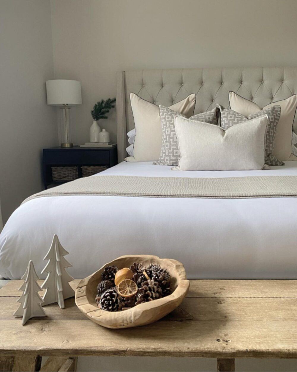 Beige buttoned bed frame, styled with festive potpourri and Christmas trees