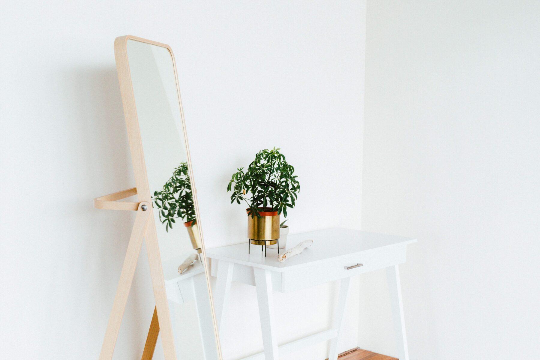 White bedroom featuring a long freestanding mirror and plant