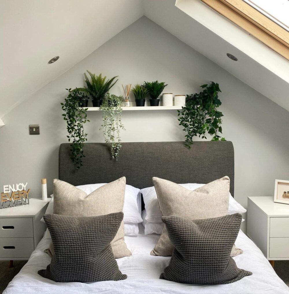 grey bed with large cushions in a bedroom with an apex roof and skylight