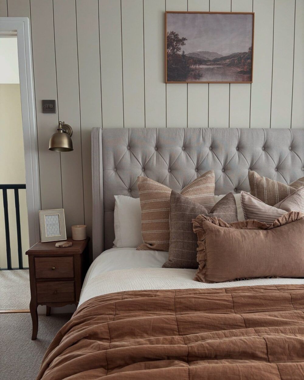 Beige buttoned bed frame, styled with autumnal decorations including brown and rust bedding