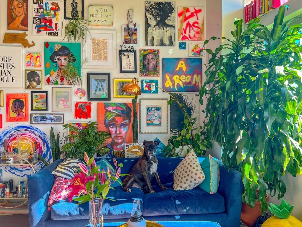 A room filled with art prints, bright colours, plants and a dog.