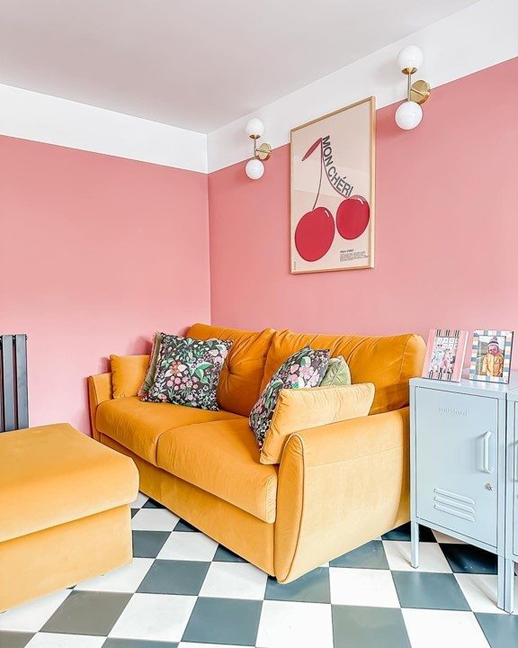 A yellow sofa bed in a pink room with blue accents