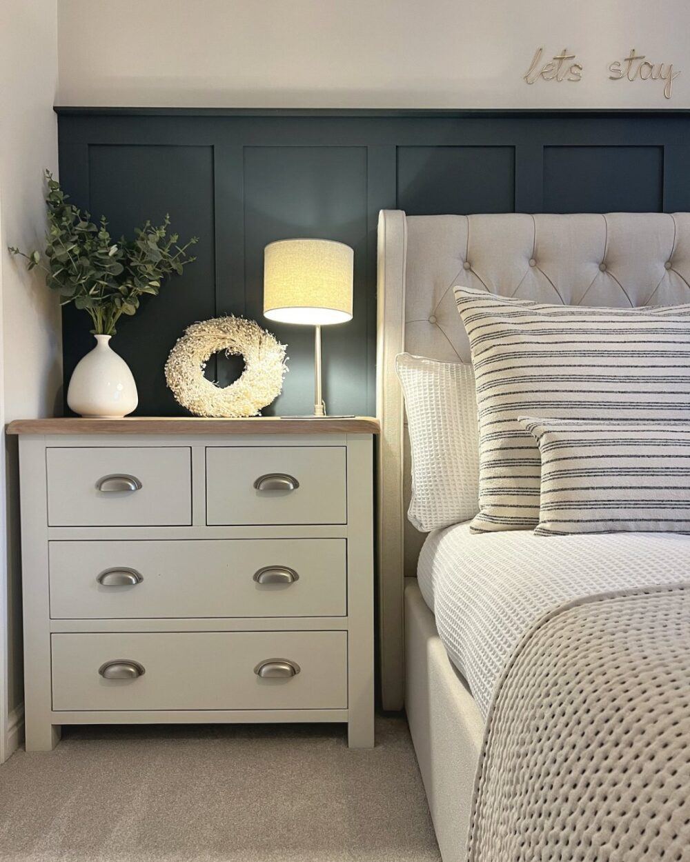 image of a bedroom with a bed on the right of the image and a chest of drawers to the left being used as storage and a bedside table