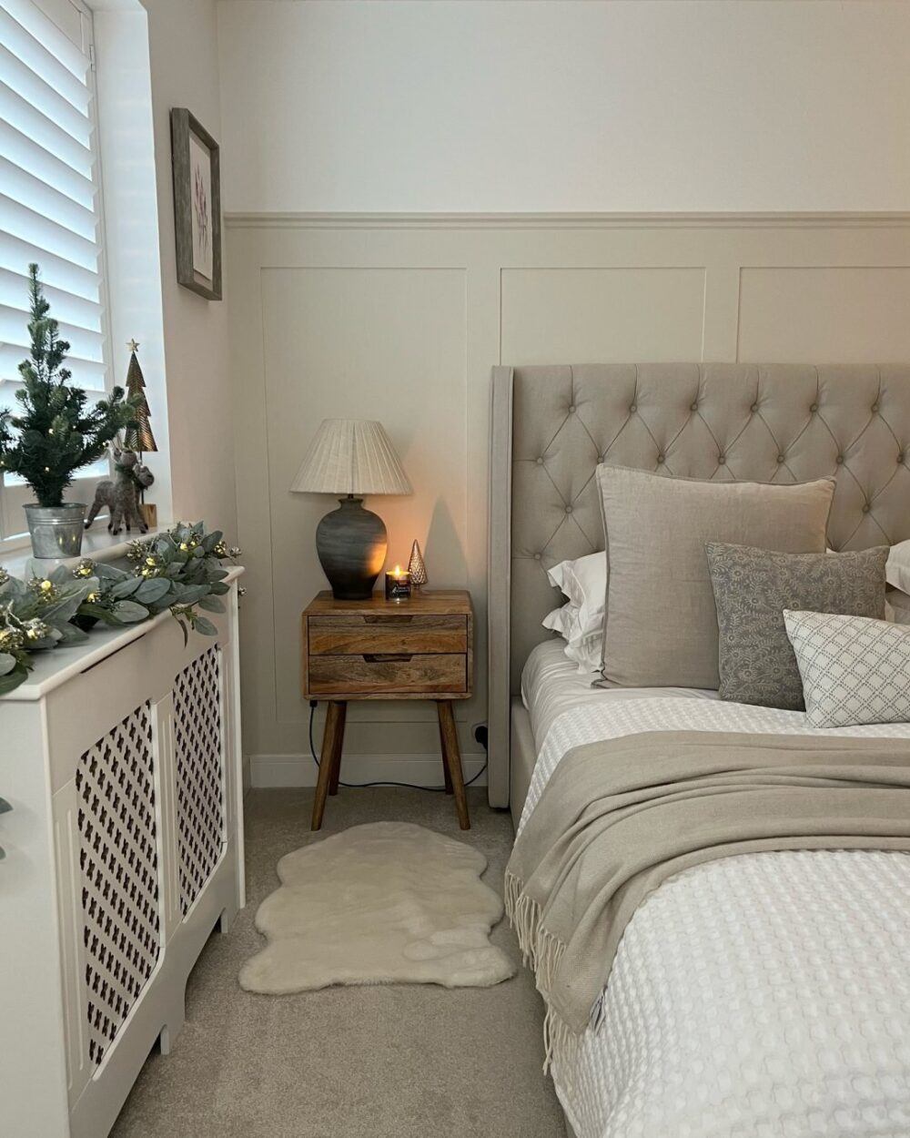 Beige buttoned bed frame, styled with a festive Christmas decorations including a fluffy rug and decorative tree