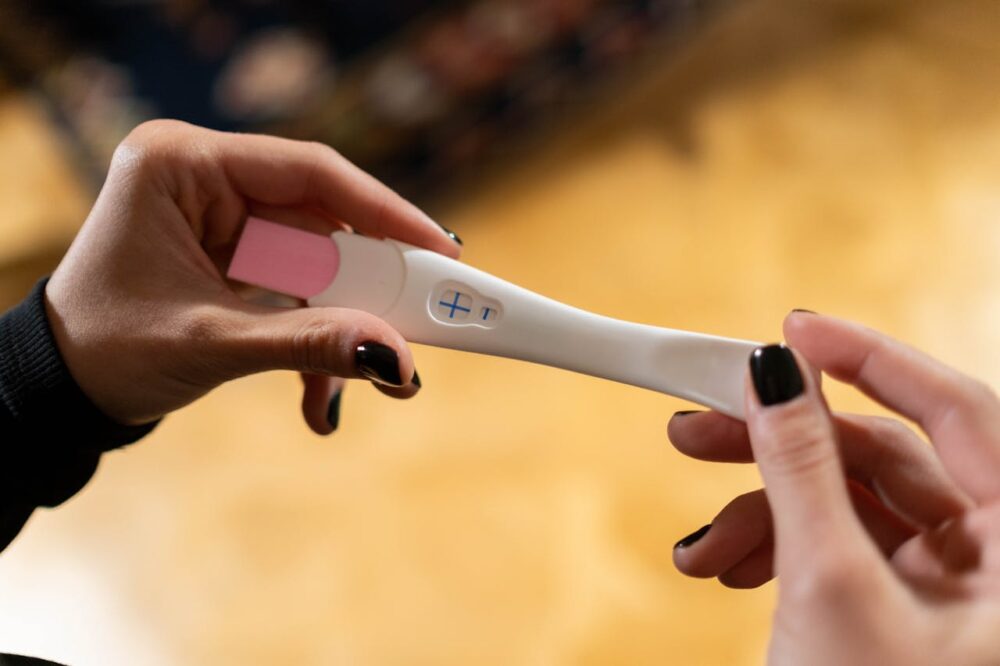 Hand holding positive pregnancy test