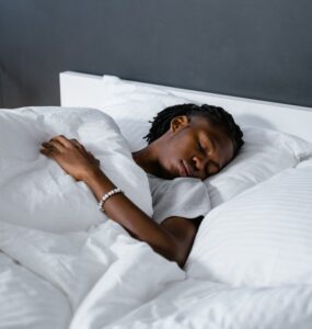 Young adult sleeping in white bedding