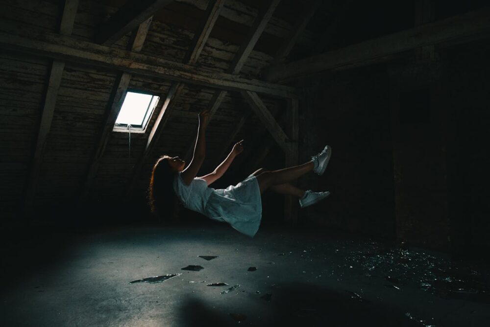 Young woman falling in a dark attic