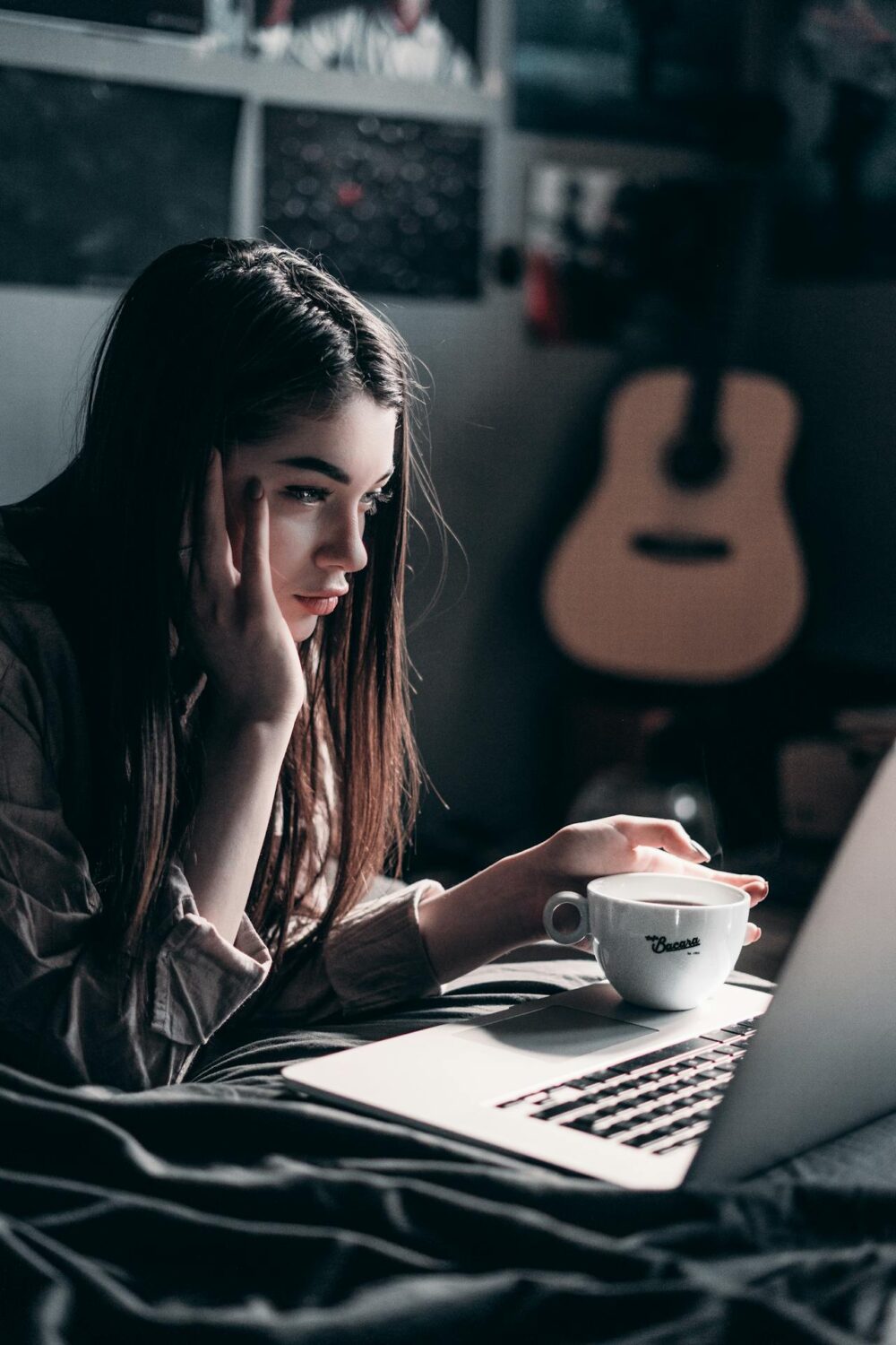 Young woman studying in bed with a cup of coffee