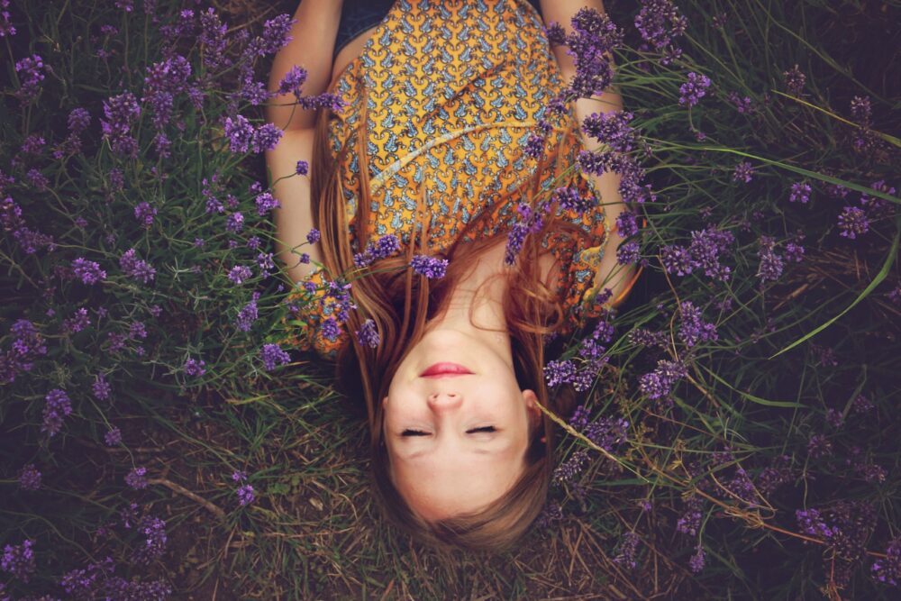 Woman meditating in a field of purple flowers