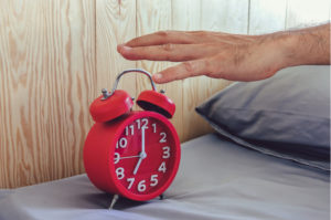 hand reaching for a red alarm clock