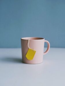 pastel pink tea cup with yellow tea bag label hanging out