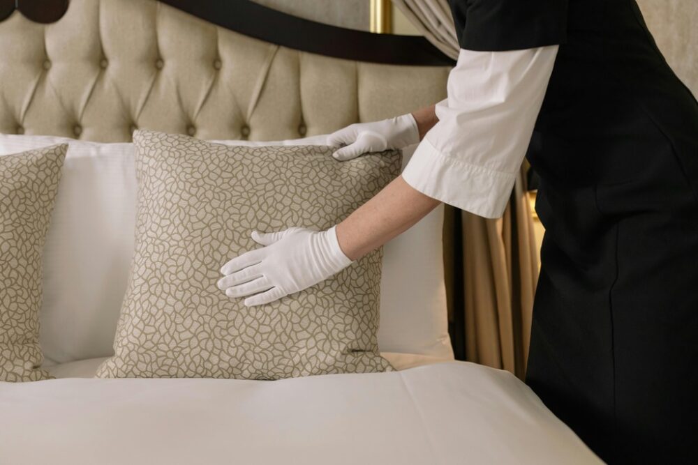 hotel cleaner placing pillow on bed